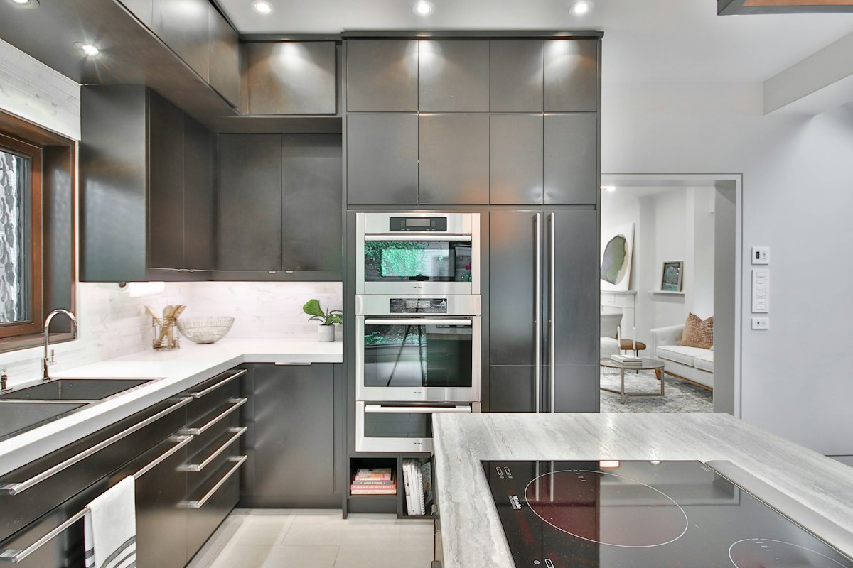 A modern kitchen with a panel-integrated refrigerator and wall ovens built into dark cabinetry