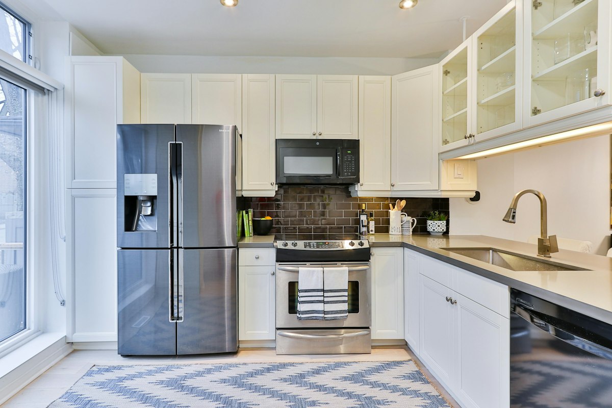 A stainless steel french door refrigerator and freezer installed in a bright white kitchen