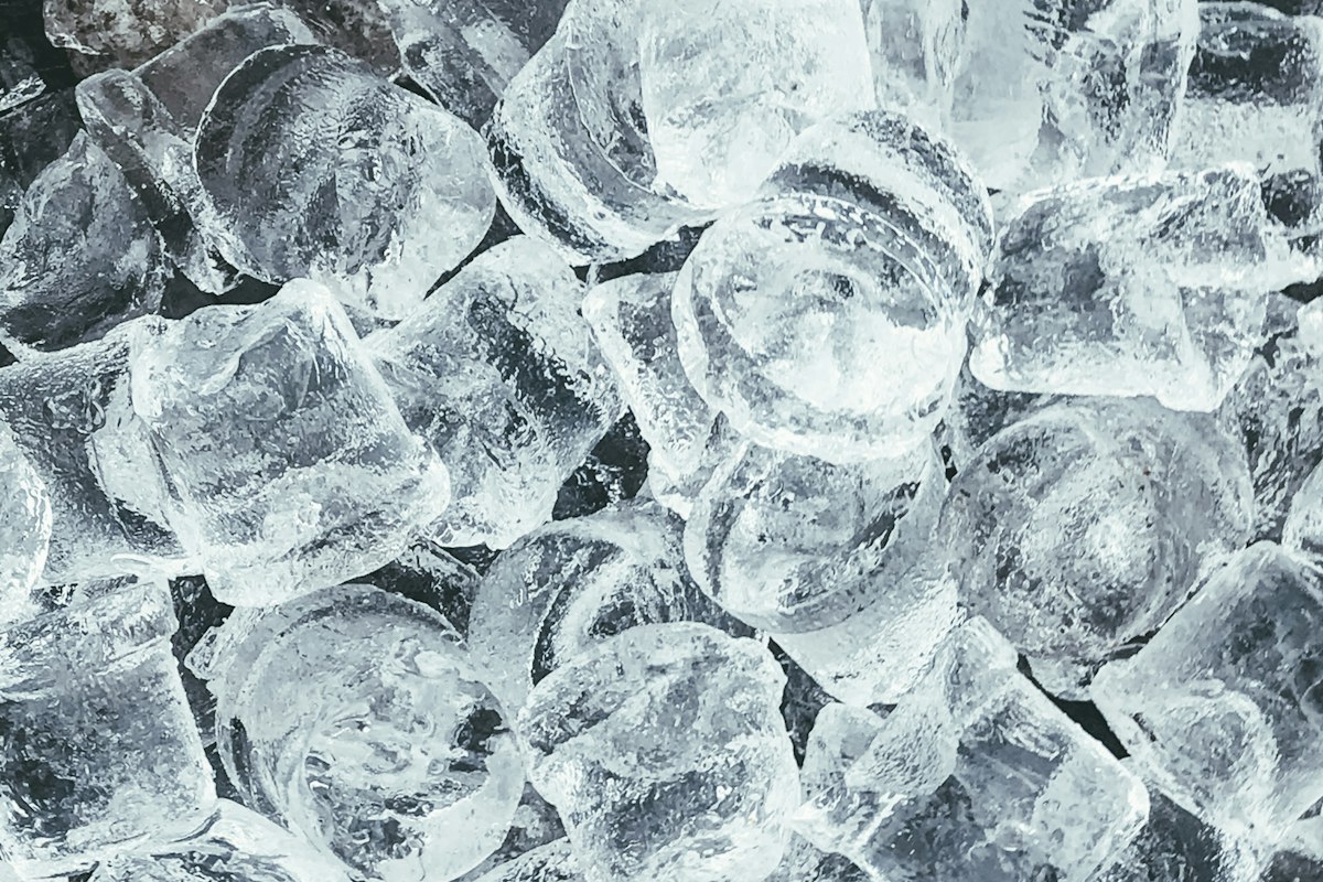 A close-up pile of clear, fully formed ice cubes like those produced by a healthy built-in ice maker