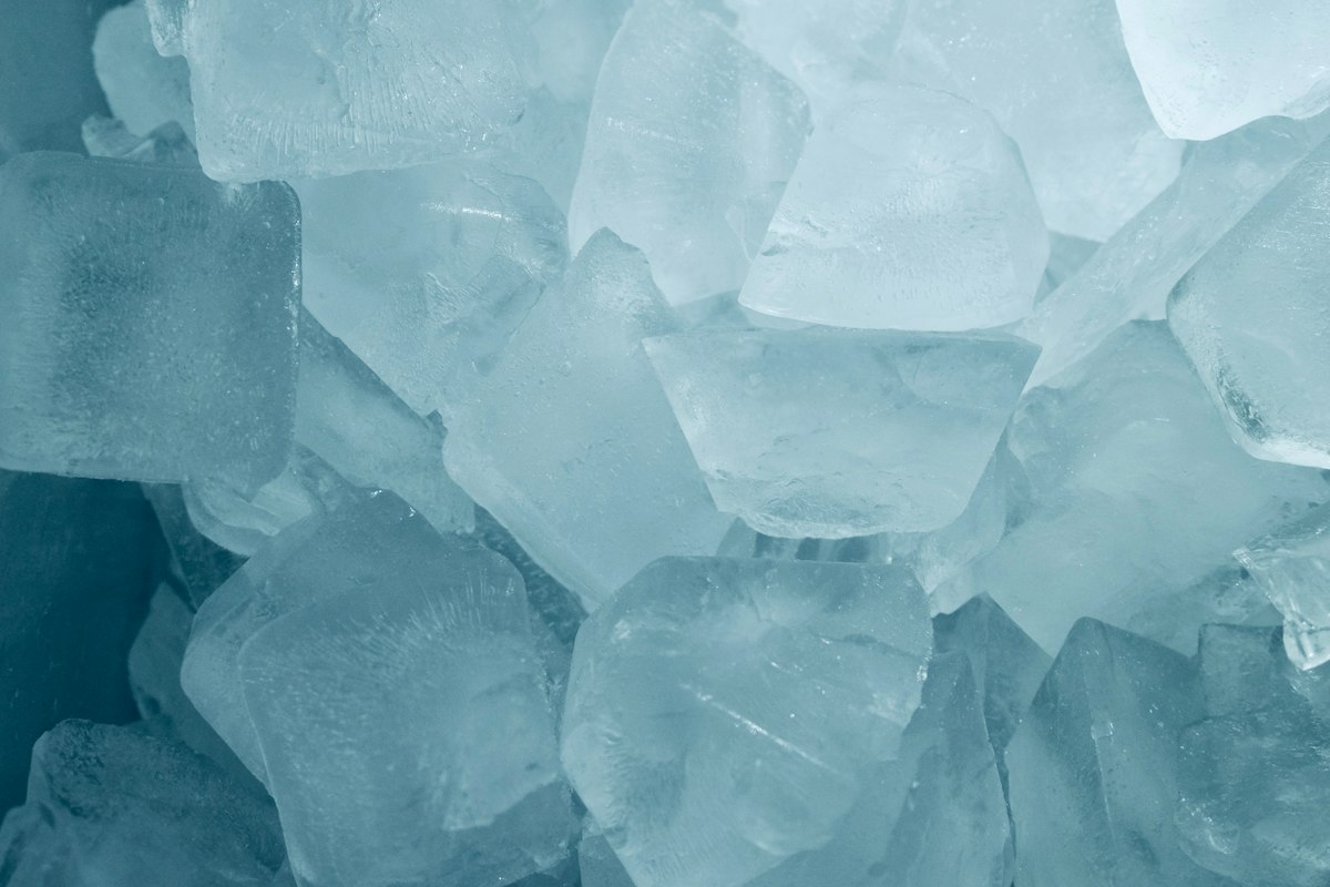 A close-up of clear ice cubes piled together with a pale blue tint
