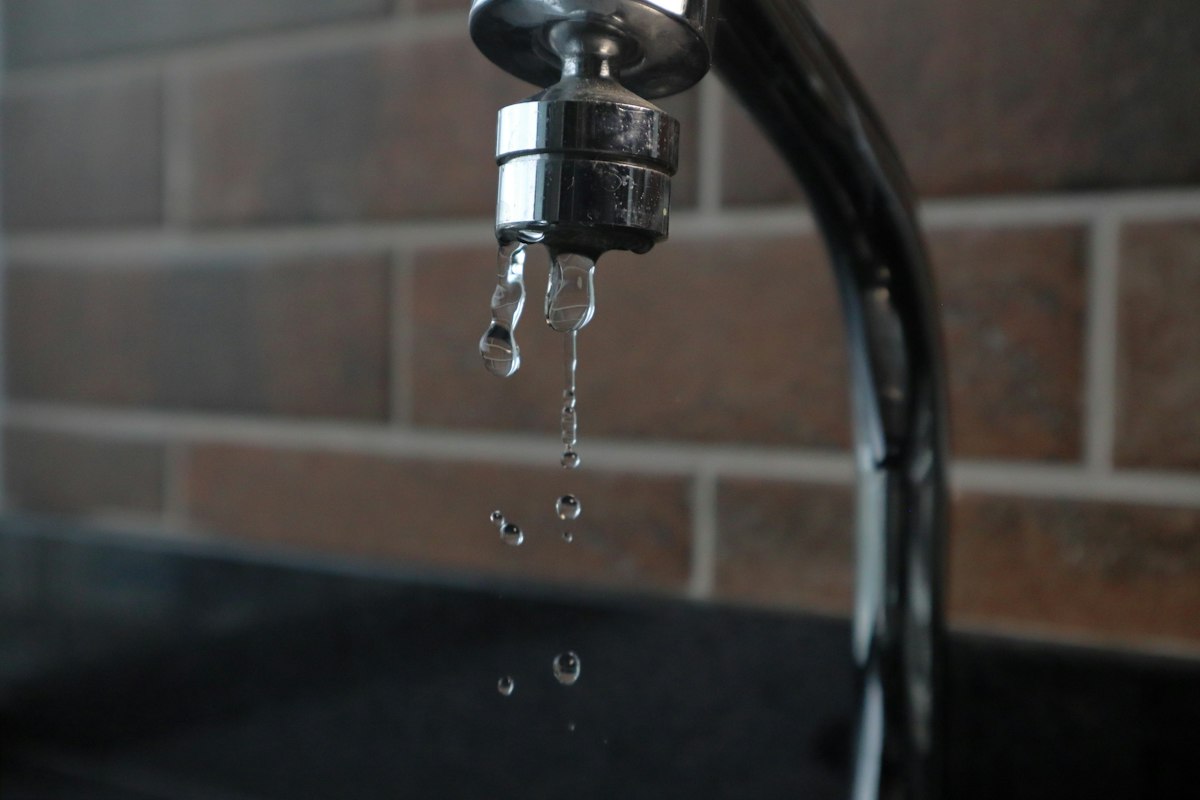 Water droplets dripping from a faucet, illustrating a slow leak from a valve that no longer seals