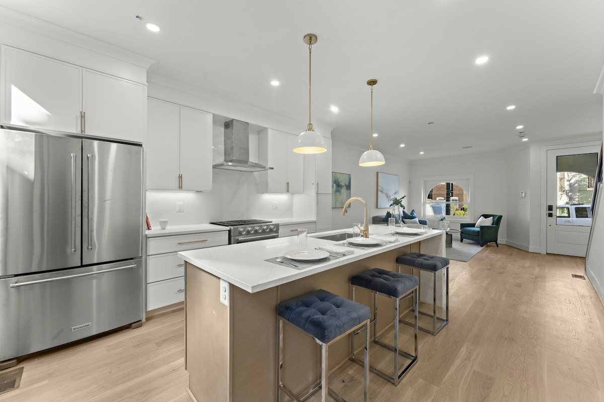 A stainless steel french door refrigerator built into white cabinetry in a bright, high-end kitchen