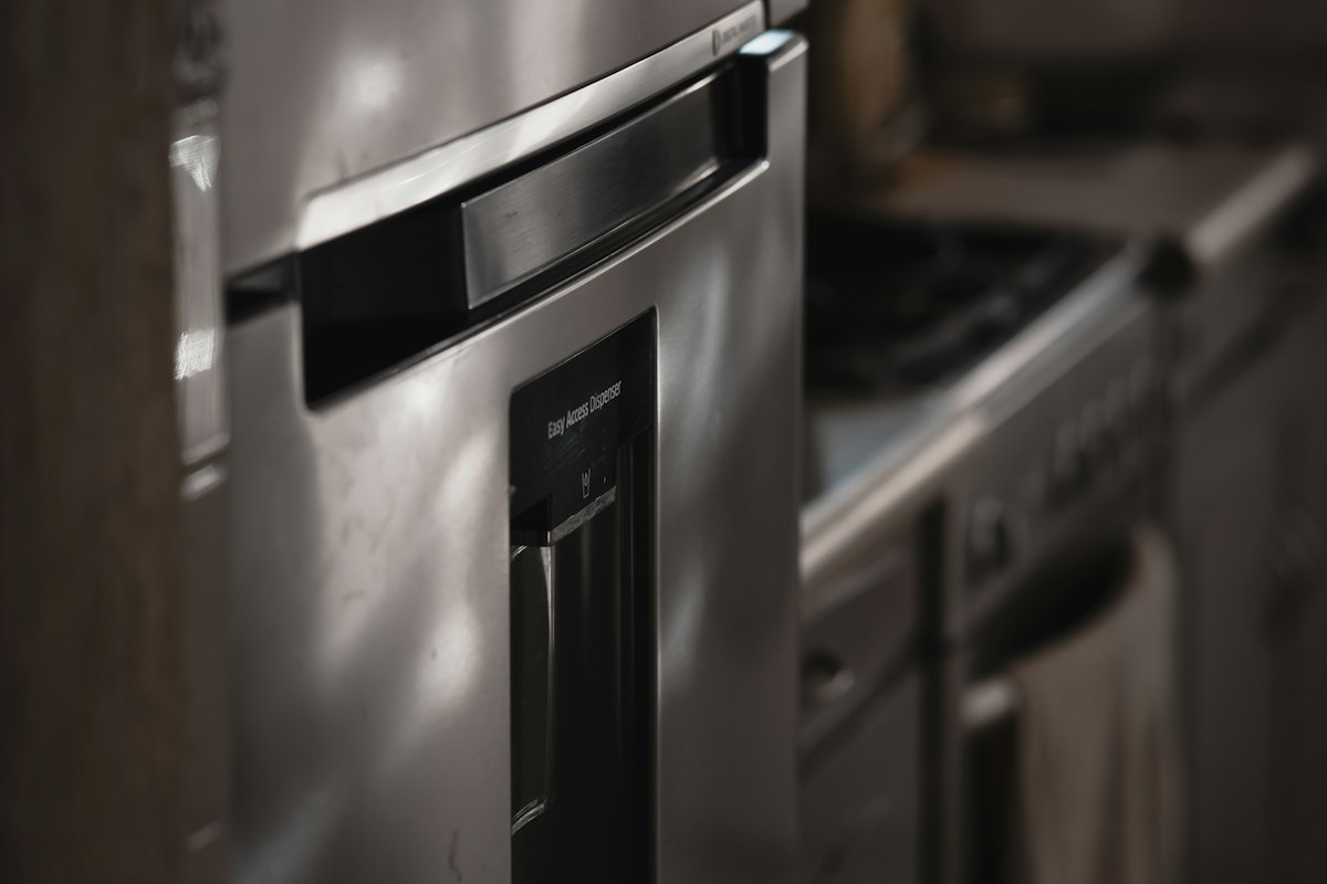 A close-up of a stainless steel refrigerator door with a built-in water dispenser and recessed handle