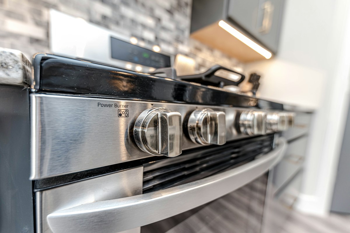 A close-up of stainless steel range control knobs, including the power burner knob, on a gas stove