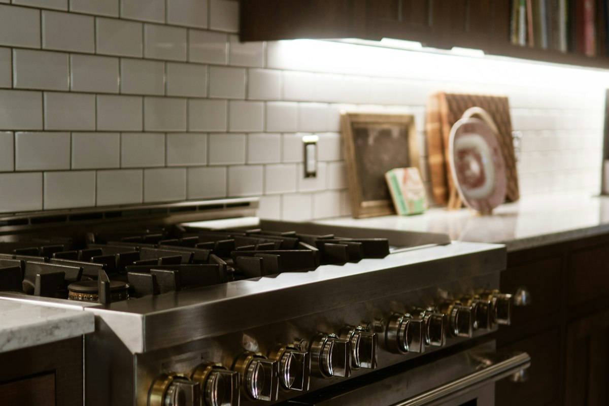 A professional-style stainless steel double oven range with six gas burners set into dark cabinetry